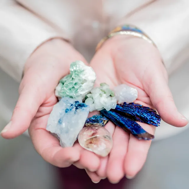 Hands gently holding a collection of healing crystals